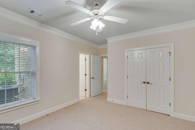 unfurnished bedroom with a closet, light carpet, ceiling fan, and crown molding