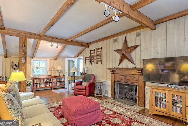 living room with wood-type flooring, vaulted ceiling with beams, and wooden walls