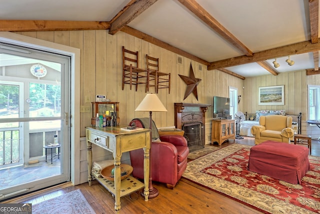 living room featuring wood walls, hardwood / wood-style flooring, and vaulted ceiling with beams