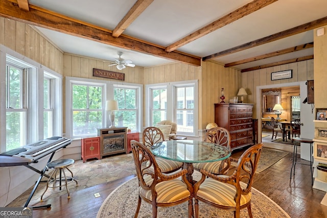 dining room with wood walls, ceiling fan, hardwood / wood-style floors, and beam ceiling