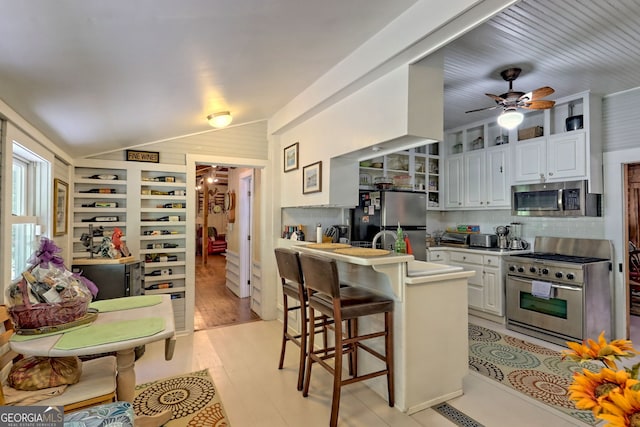 kitchen with stainless steel appliances, light hardwood / wood-style floors, decorative backsplash, white cabinetry, and ceiling fan