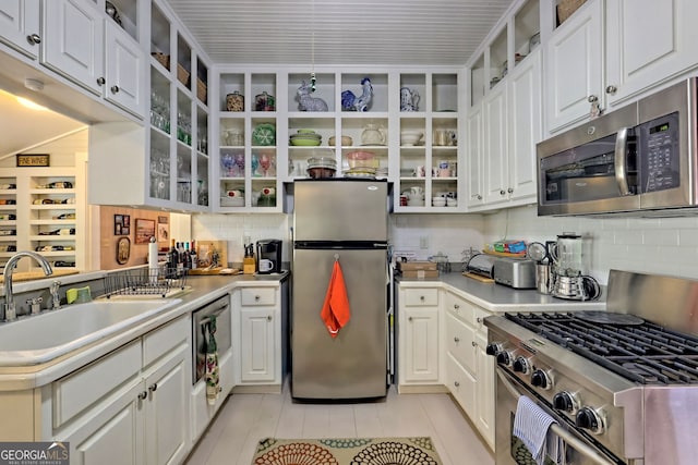 kitchen featuring appliances with stainless steel finishes, white cabinets, decorative backsplash, and sink