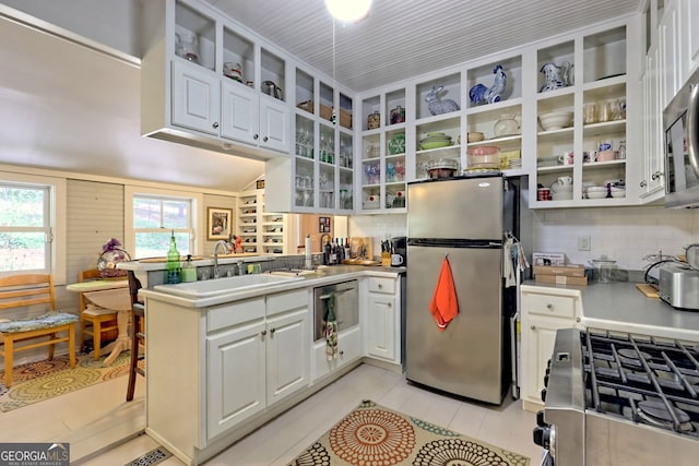 kitchen featuring tasteful backsplash, stainless steel appliances, white cabinets, sink, and kitchen peninsula