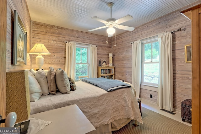 bedroom featuring wood walls, carpet, and ceiling fan