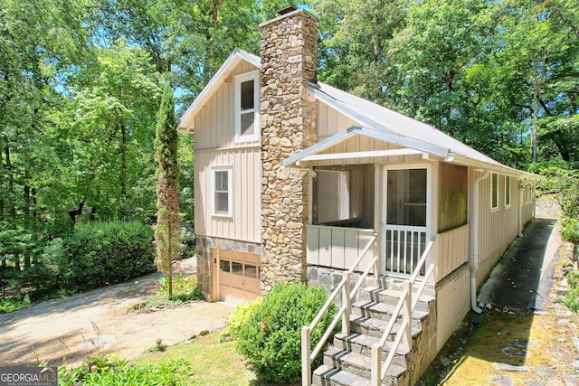 208 Colony Rd, Dillard, GA 30537 - view of front of house with board and batten siding, a garage, driveway, and a chimney