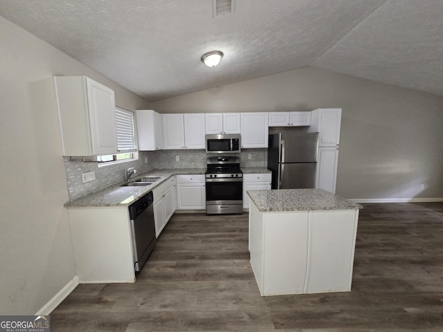 kitchen featuring decorative backsplash, dark wood-type flooring, vaulted ceiling, stainless steel appliances, and white cabinetry