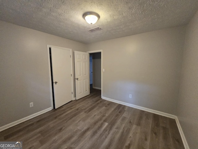 unfurnished bedroom with a textured ceiling and dark hardwood / wood-style floors