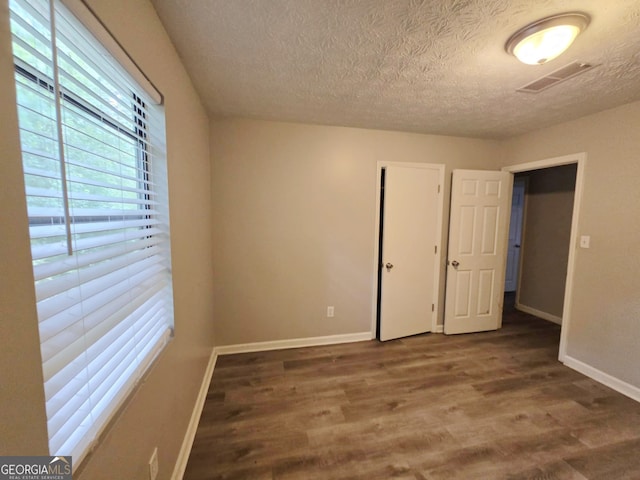 spare room featuring dark hardwood / wood-style flooring and a textured ceiling