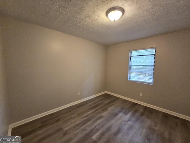 spare room featuring dark hardwood / wood-style floors and a textured ceiling