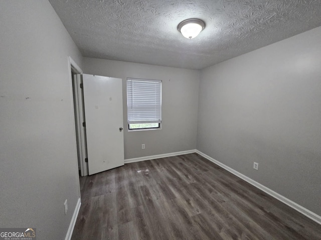 spare room featuring a textured ceiling and dark wood-type flooring