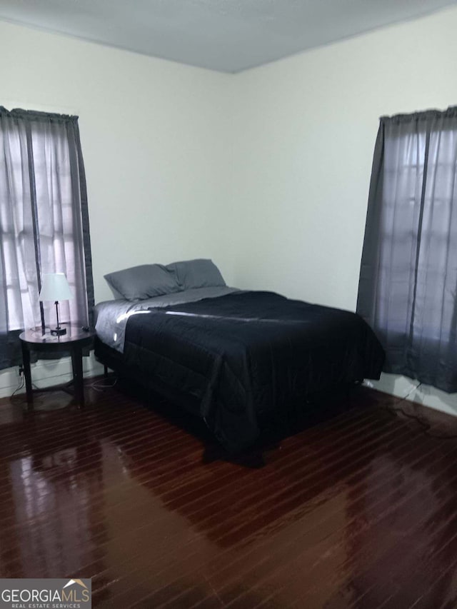 bedroom with dark hardwood / wood-style flooring and multiple windows