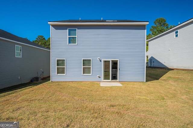 back of house with central air condition unit and a lawn