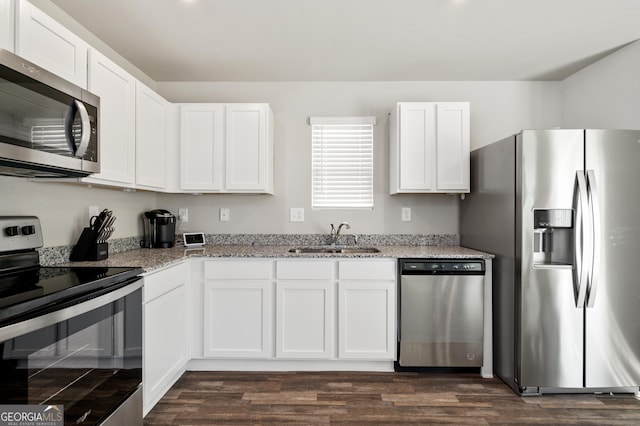 kitchen with stainless steel appliances, sink, white cabinets, light stone countertops, and dark hardwood / wood-style floors