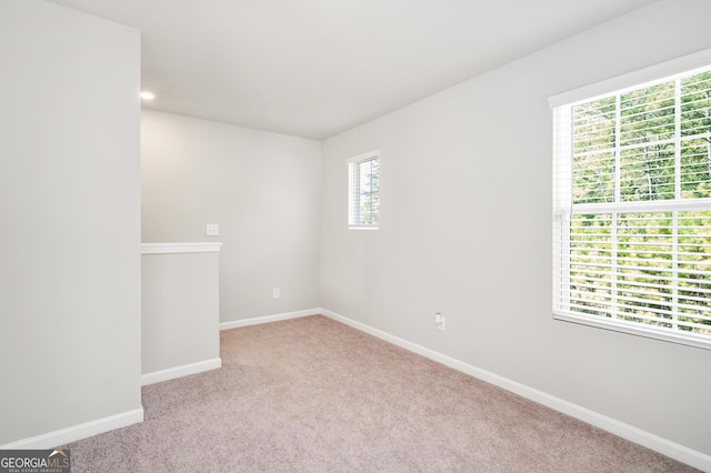 unfurnished room featuring a wealth of natural light and light colored carpet