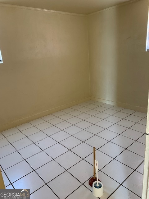 tiled spare room featuring ornamental molding