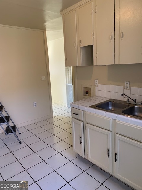 kitchen with sink, white cabinetry, tile countertops, and tasteful backsplash