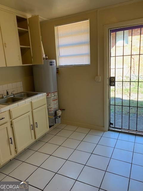 kitchen with sink, gas water heater, white cabinets, and light tile patterned floors