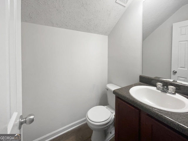 bathroom featuring lofted ceiling, vanity, toilet, and a textured ceiling