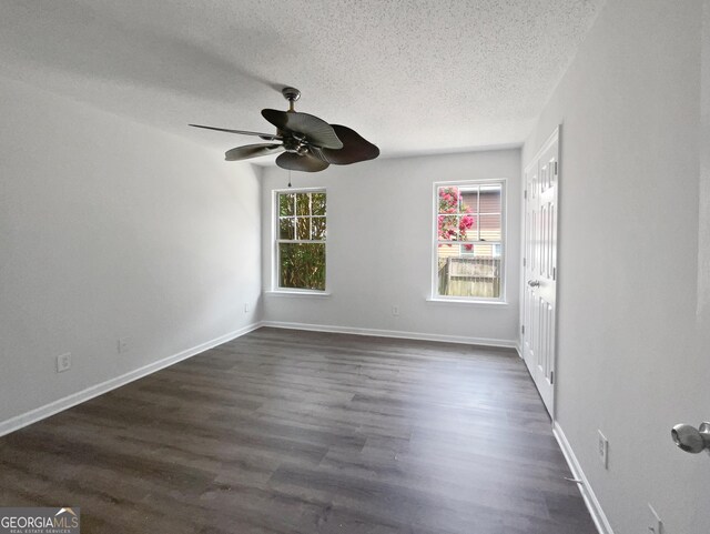 spare room featuring dark wood-type flooring, ceiling fan, and a textured ceiling