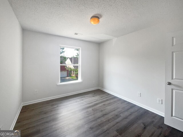 unfurnished room featuring dark wood-type flooring and a textured ceiling