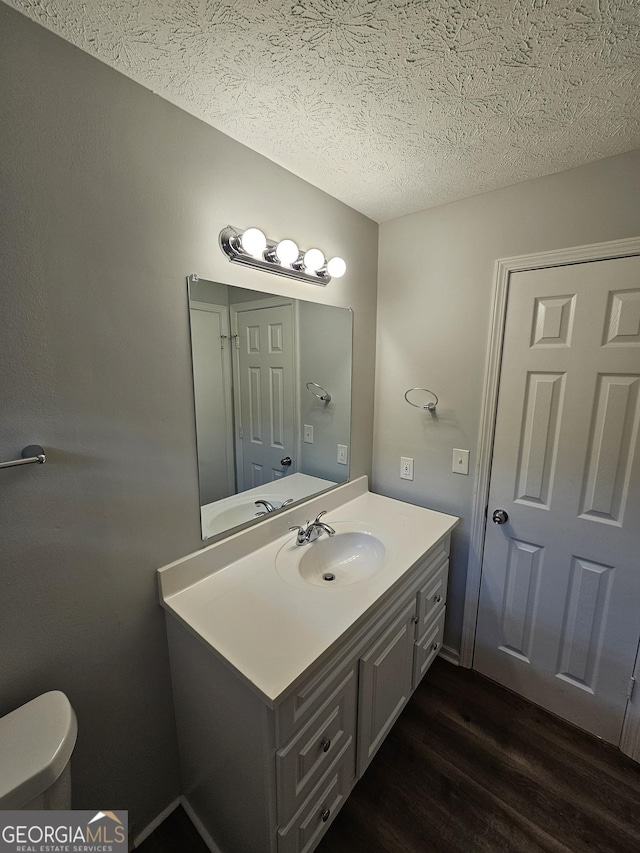 bathroom with hardwood / wood-style flooring, vanity, a textured ceiling, and toilet