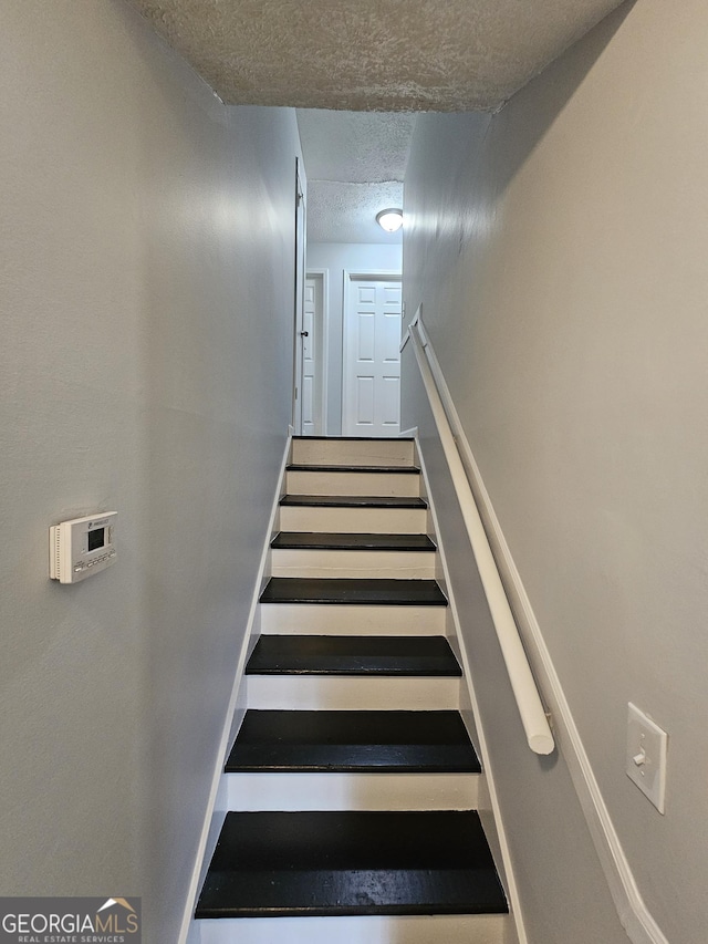 staircase featuring a textured ceiling