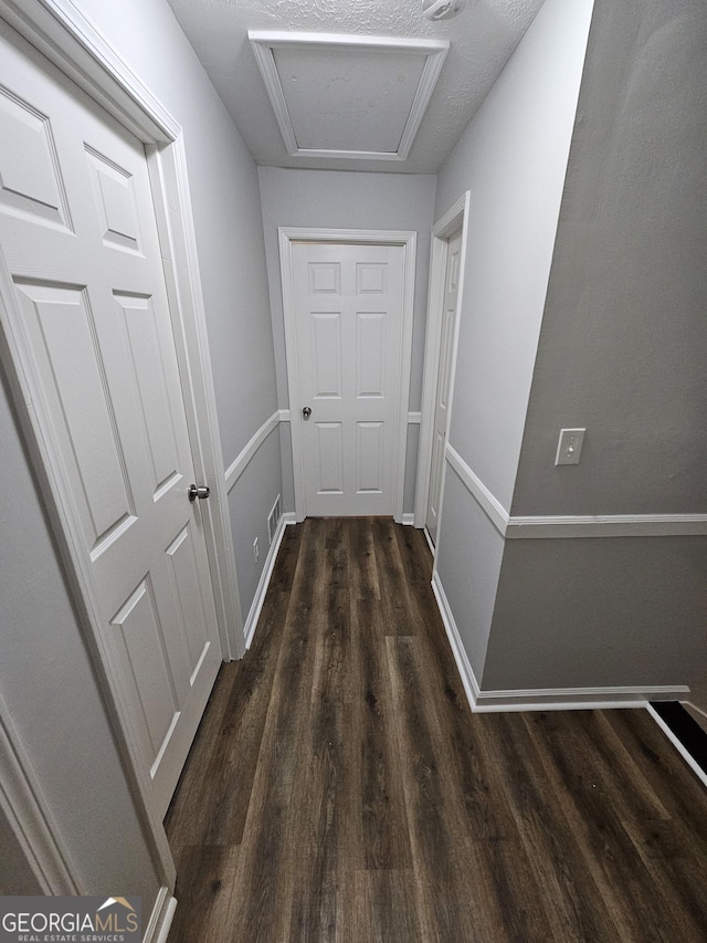 hallway featuring dark hardwood / wood-style floors and a textured ceiling