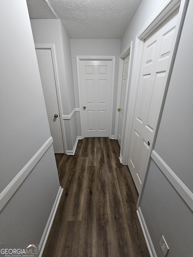 hall with dark wood-type flooring and a textured ceiling