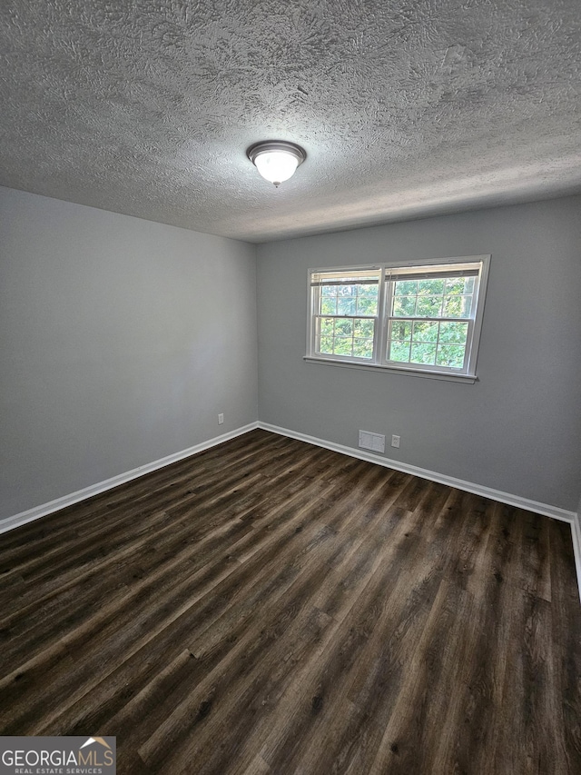 unfurnished room with dark hardwood / wood-style floors and a textured ceiling