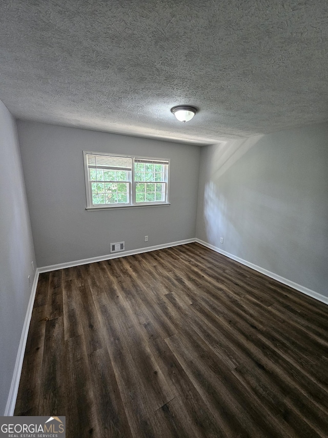 unfurnished room with dark wood-type flooring and a textured ceiling