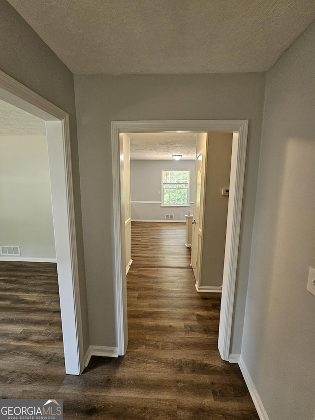 hallway with dark hardwood / wood-style flooring and a textured ceiling