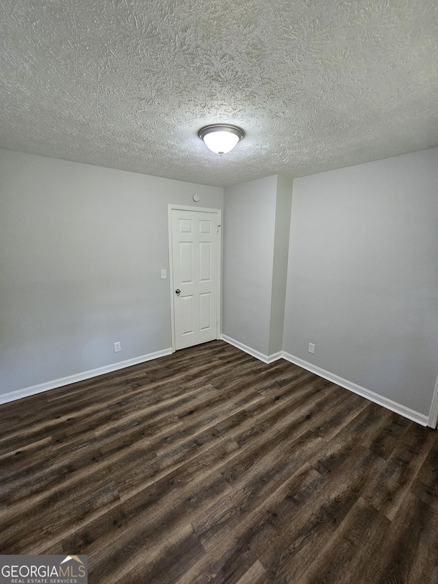 empty room featuring dark hardwood / wood-style flooring and a textured ceiling