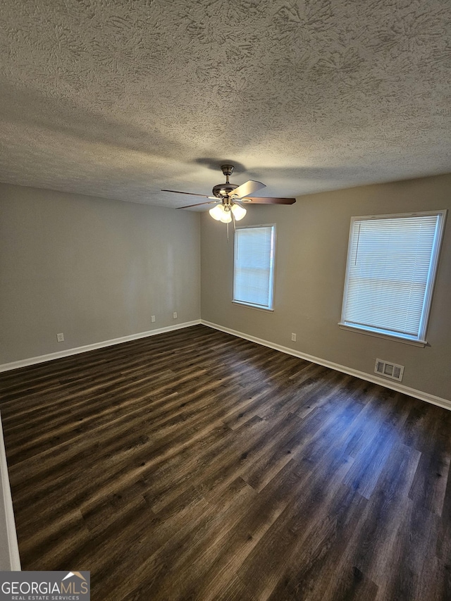 spare room featuring a textured ceiling, dark wood-type flooring, and ceiling fan