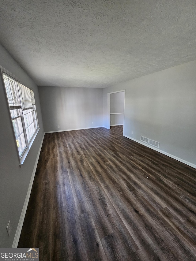 spare room with dark hardwood / wood-style flooring and a textured ceiling