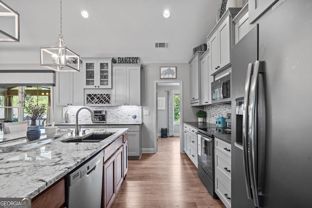 kitchen with stainless steel appliances, sink, decorative light fixtures, an inviting chandelier, and white cabinets