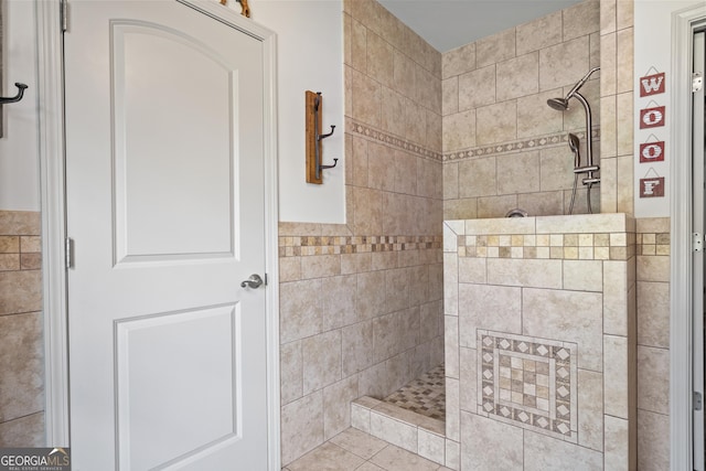 bathroom featuring tiled shower, tile patterned flooring, and tile walls