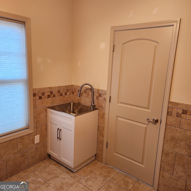 laundry area featuring light tile patterned flooring, sink, and tile walls