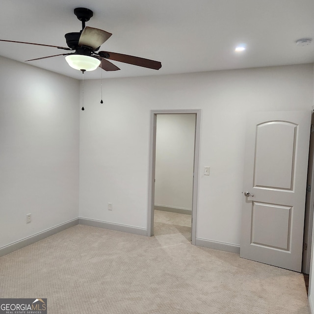 empty room featuring ceiling fan and light colored carpet