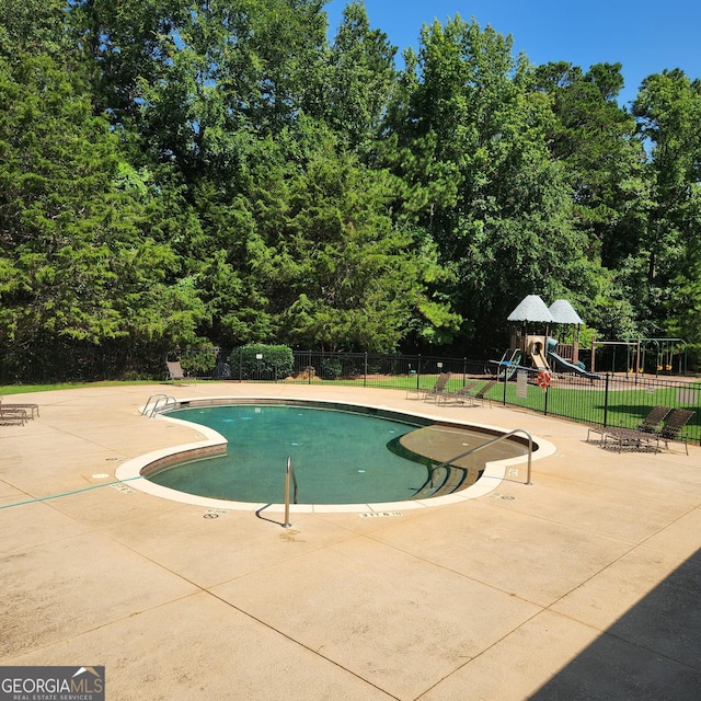 view of swimming pool with a playground and a patio