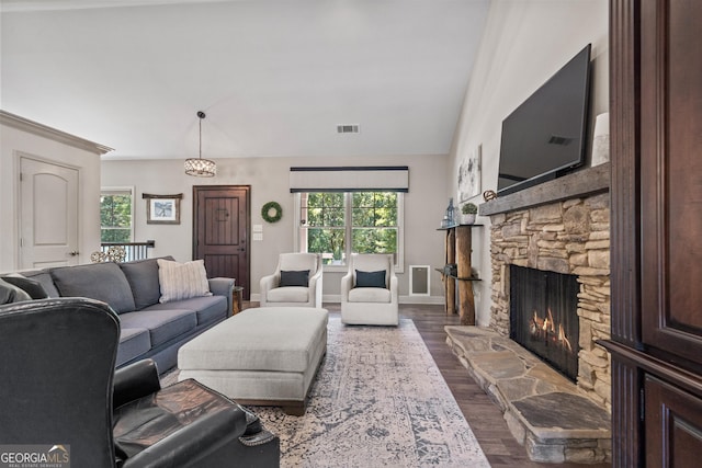 living room with a stone fireplace, dark wood-type flooring, and lofted ceiling