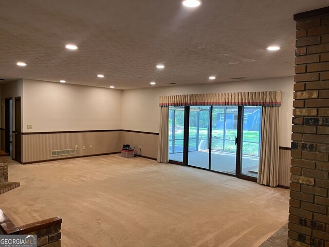 interior space featuring light carpet, a textured ceiling, and wood walls