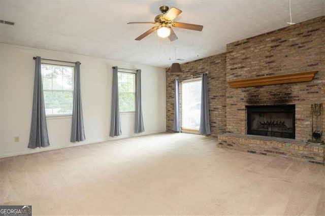 unfurnished living room featuring ceiling fan, a fireplace, carpet flooring, and a wealth of natural light