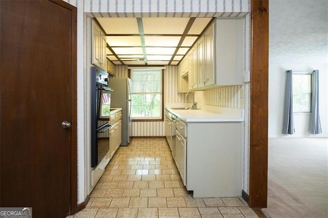 kitchen featuring sink, cream cabinetry, light carpet, double oven, and refrigerator