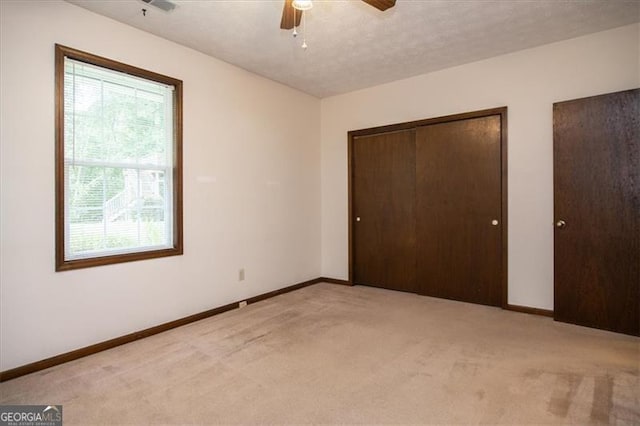 unfurnished bedroom with light carpet, ceiling fan, and a textured ceiling