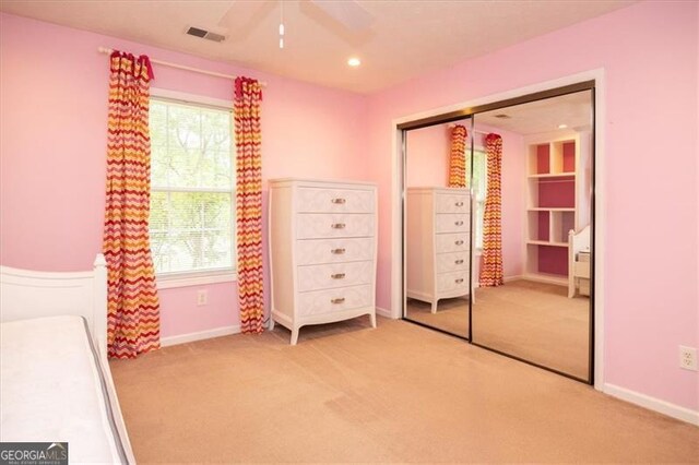 unfurnished bedroom featuring ceiling fan, light colored carpet, a closet, and multiple windows