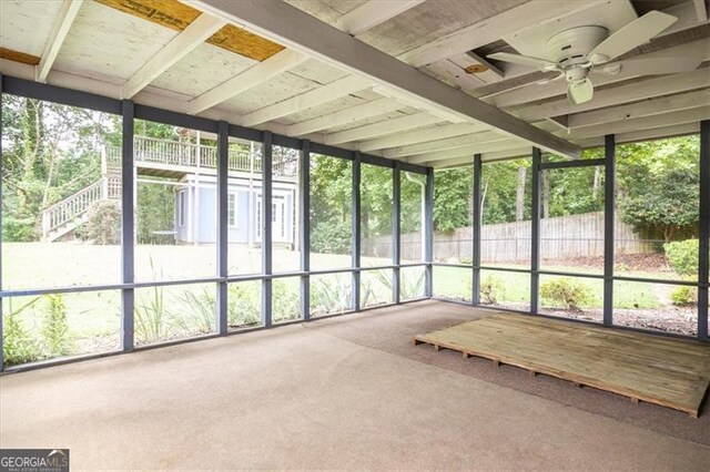 unfurnished sunroom with beamed ceiling and ceiling fan