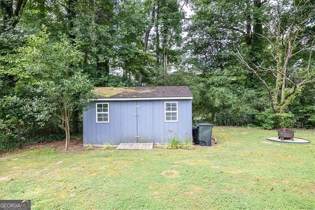 view of outbuilding with a yard and an outdoor fire pit