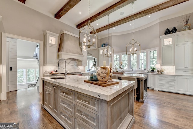 962 Chattooga Trce, Suwanee, GA 30024 - kitchen with a center island with sink, custom exhaust hood, a chandelier, beamed ceiling, and tasteful backsplash