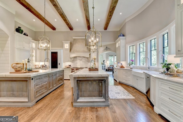 962 Chattooga Trce, Suwanee, GA 30024 - kitchen featuring custom range hood, a spacious island, a chandelier, glass insert cabinets, and tasteful backsplash