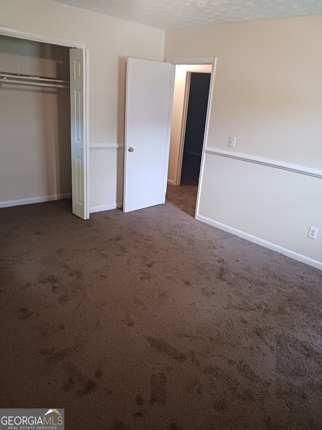 unfurnished bedroom featuring a closet and dark carpet